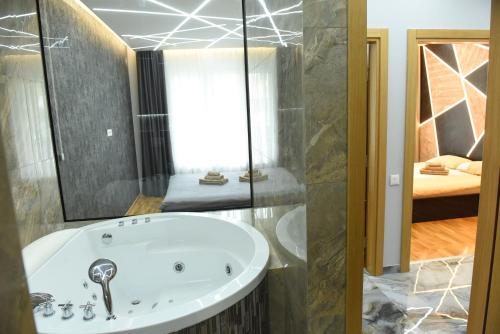 a bathroom with a tub and a bedroom at Premium Lux Apartman Čačak in Čačak