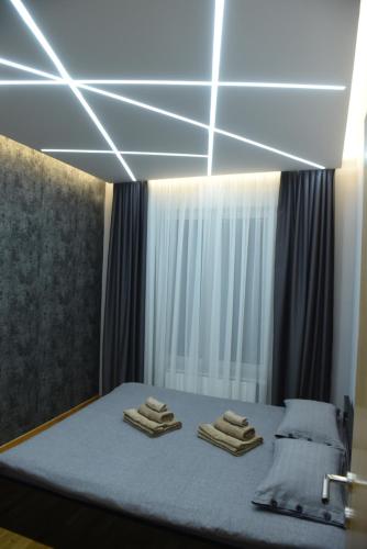 a bedroom with a bed with lights on the ceiling at Premium Lux Apartman Čačak in Čačak