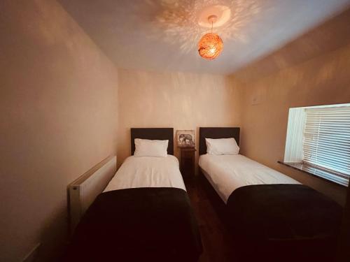 two beds in a small room with a window at River Cottage in Mullingar