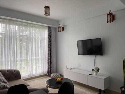 een woonkamer met een bank en een flatscreen-tv bij Prime Nest Grey point 305 in Kericho