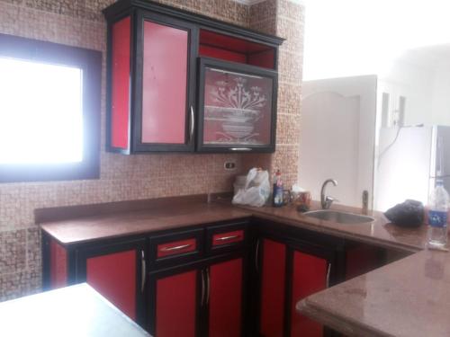 a kitchen with red cabinets and a sink at Aida in El Alamein