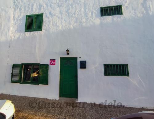 biały budynek z zielonymi drzwiami i oknami w obiekcie Casa mar y cielo w mieście Playa Blanca