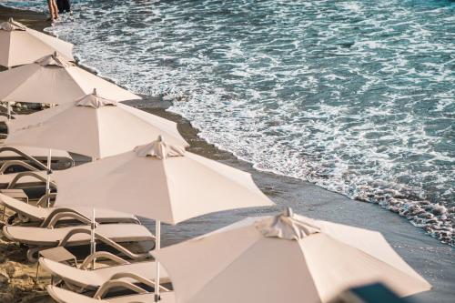 un grupo de sombrillas y sillas blancas en la playa en KAAB Boutique Hotel en Ulcinj