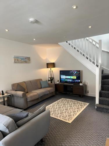 a living room with a couch and a tv at Amo Mews House - Central, Private Patio & Free Parking in Worthing