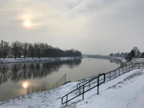 a river covered in snow with a fence next to it at Ons Maashuisje in Maaseik