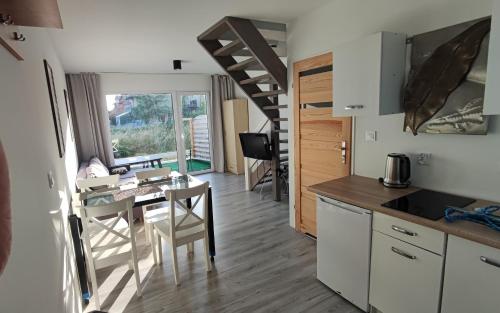 a kitchen and dining room with a table and a kitchen and a staircase at Domki Bosman in Dziwnówek