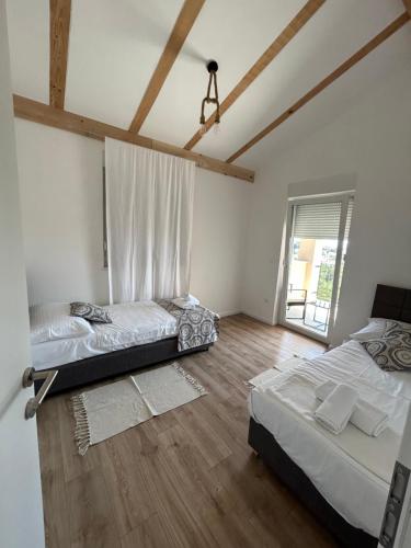 una camera con 2 letti e una finestra e pavimenti in legno di TwENty-Punat Apartments a Punat