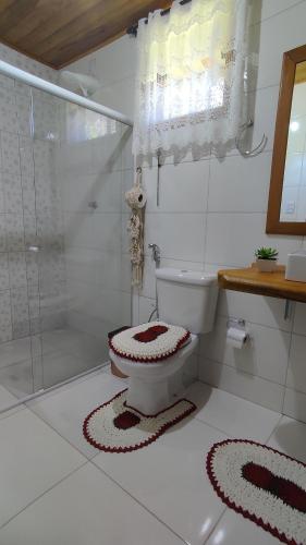 a white bathroom with a toilet and a shower at Chalés Vale das Pedras in Venda Nova do Imigrante