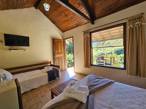 a bedroom with two beds and a large window at Hotel Fazenda Santo Antônio in Vassouras