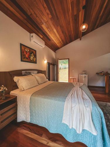 a bedroom with a large bed with a wooden ceiling at Chalés Vale das Pedras in Venda Nova do Imigrante
