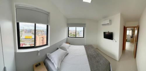 a bedroom with a bed and two windows at Apto Corais do Mar 290m Praia Jatiuca in Maceió