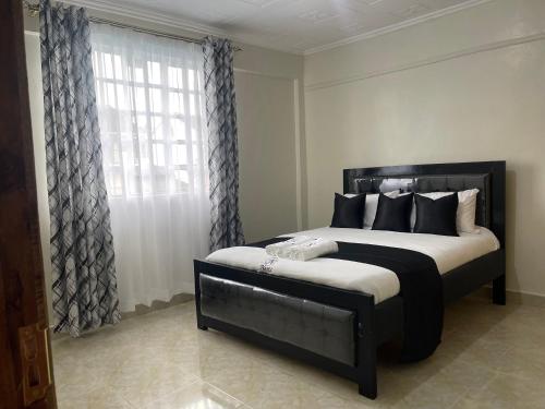 a bedroom with a black bed with a window at Oak Nest 306 in Kericho