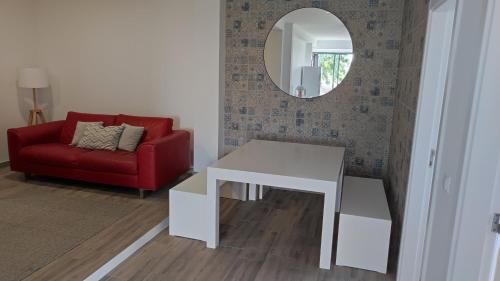 a living room with a red couch and a table and a mirror at Costa do Moinho in Horta