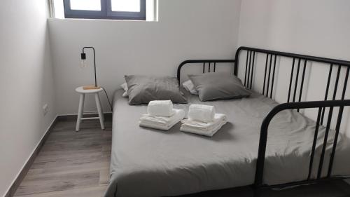 Una cama con dos toallas blancas y un taburete. en Costa do Moinho, en Horta