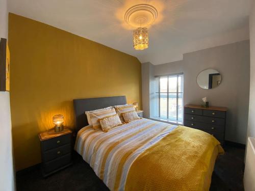een slaapkamer met een bed en een gele muur bij Bluebell Cottage Heritage Town nr Brecon Beacons with hot tub in Blaenavon