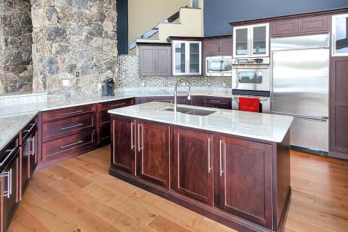 a large kitchen with wooden cabinets and a sink at Iconic Glass Mansion - Huge Views - Best Location in Osage Beach