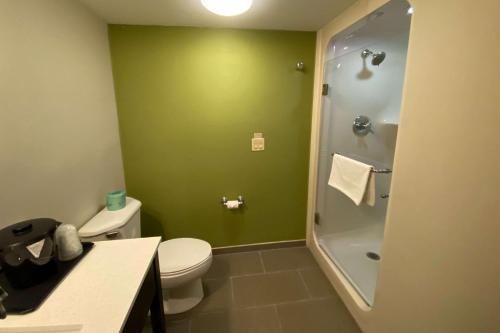 a bathroom with a toilet and a green wall at Sleep Inn & Suites Niantic North in Niantic