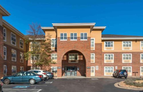 a large brick building with cars parked in a parking lot at Extended Stay America Suites - Kansas City - Overland Park - Quivira Rd in Lenexa