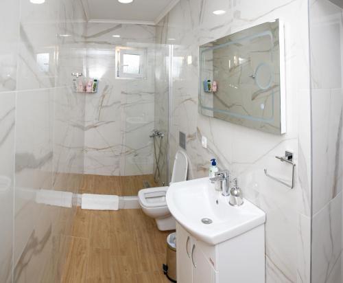 a white bathroom with a toilet and a sink at Reshkov Pool Apartments in Gevgelija