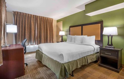 a hotel room with a bed and a desk with two lamps at Extended Stay America Suites - Indianapolis - Northwest - I-465 in Indianapolis