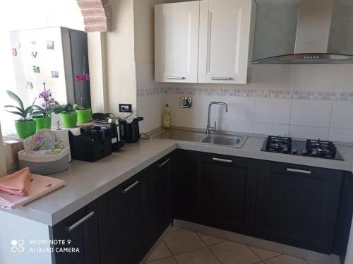 a kitchen with black cabinets and a sink at Punto Zero in San Giovanni Valdarno