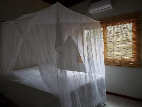a bedroom with a bed covered in white mosquito net at Barra Grande Bangalôs in Marau