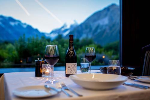 a table with wine glasses and a bottle of wine at The Hermitage Hotel Mt Cook in Mount Cook Village