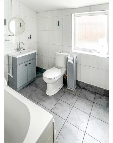 a bathroom with a toilet and a sink and a window at Private room with Netflix in Litherland