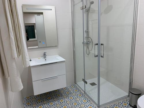 a bathroom with a glass shower and a sink at Casa do Bairro in Seia
