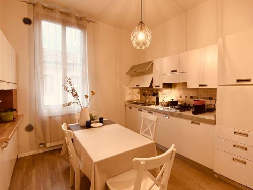uma cozinha com mesa e cadeiras e uma cozinha com armários brancos em Casa Oscar: Entire apartment Venice.Mestre station em Mestre