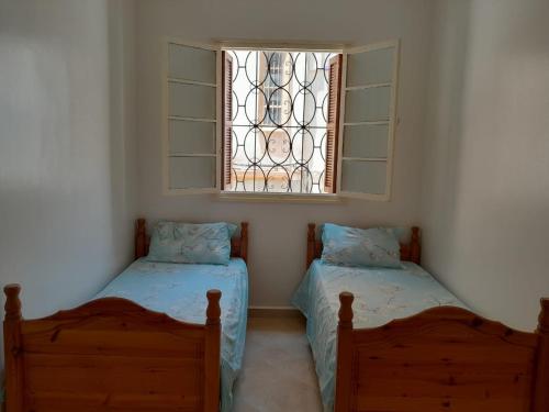 two beds in a room with a window at appartement Lazrak in Tangier