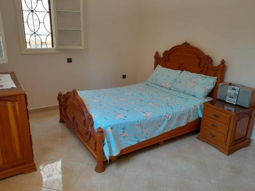 a bedroom with a bed with a wooden frame and a tv at appartement Lazrak in Tangier