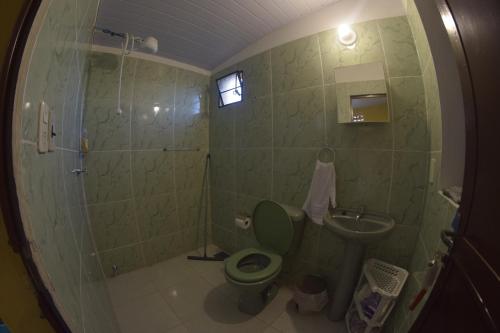 baño con aseo verde y lavamanos en Hotel La Mansión, en Villarrica