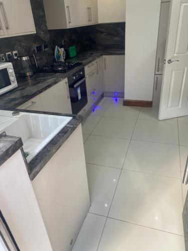 a kitchen with white appliances and a white tile floor at Pure luxury APT2 in Wolverhampton