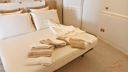 ein weißes Bett mit weißen Kissen und Handtüchern darauf in der Unterkunft Attico d'arte sulla Valle dei Templi in Agrigento