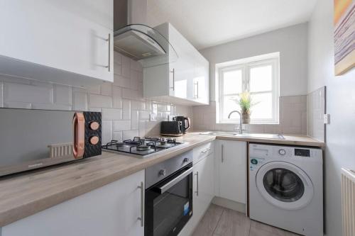 a white kitchen with a stove and a washing machine at Lovely 2 Bedroom Condo with River & City View in North Woolwich