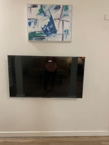 a television in a white wall with a painting at Country studio pet friendly in Port Alberni