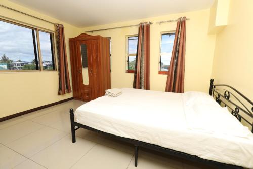 a bedroom with a bed and two windows at Tropical Plaza Apt in Nadi