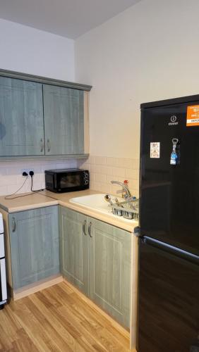 a kitchen with a black refrigerator and a sink at Memory Homes MM H2 in Dukinfield