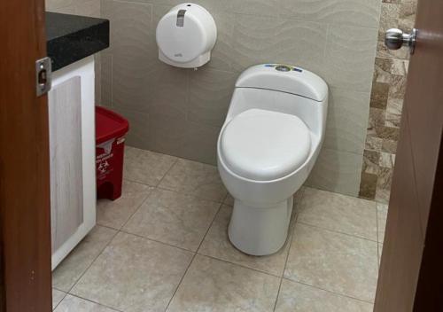 a bathroom with a toilet and a red trash can at Hotel Caribe Rodadero in Santa Marta