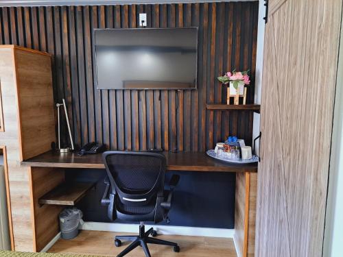 a desk with a chair and a television on a wall at Dunes Motel - Bend in Bend