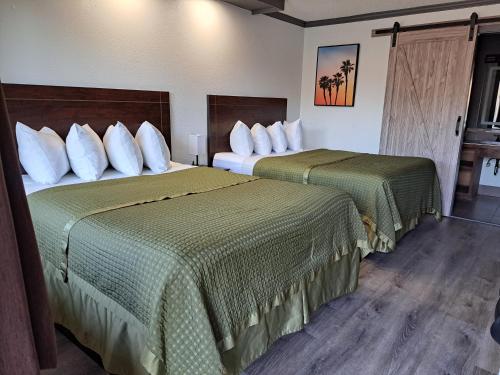 a hotel room with two beds with green sheets at Dunes Motel - Bend in Bend