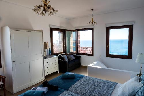 Seaview Villa في Tavari: غرفة نوم بسرير واريكة ونوافذ