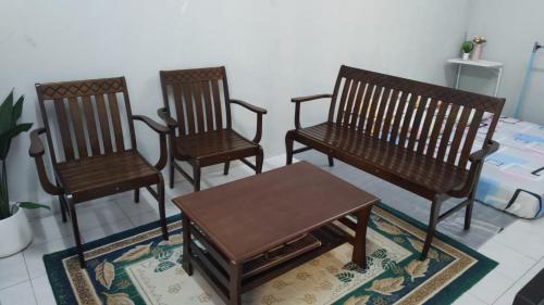 three wooden chairs and a table in a room at Homestay Kasturi Teluk Kalong Kemaman in Kijal