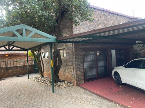 a white car parked under a garage with a carport at We Love Properties Guest House in Centurion