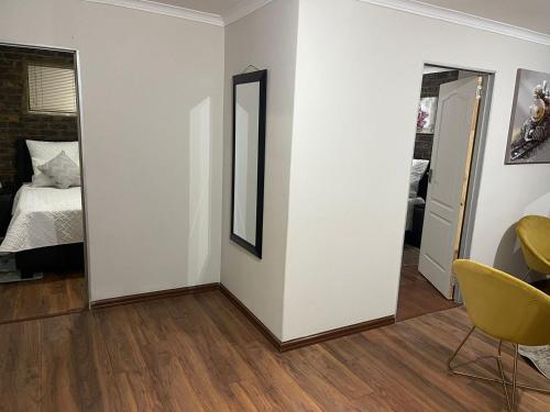 a room with white walls and a mirror and a bed at We Love Properties Guest House in Centurion