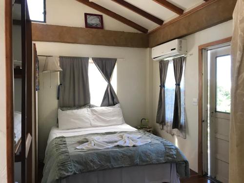 ein Schlafzimmer mit einem Bett in einem Zimmer mit einem Fenster in der Unterkunft Alta Vista Vacation Home in Caye Caulker