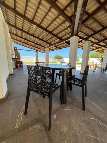 une table et deux chaises assises sous un toit dans l'établissement Casa de Praia no Morro Branco, à Beberibe