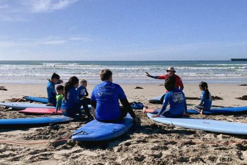 a group of people sitting on surfboards on a beach at Bluey in Warrnambool