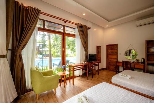 1 Schlafzimmer mit 2 Betten, einem Schreibtisch und einem Fenster in der Unterkunft Mai Binh Phuong Bungalow in Phu Quoc